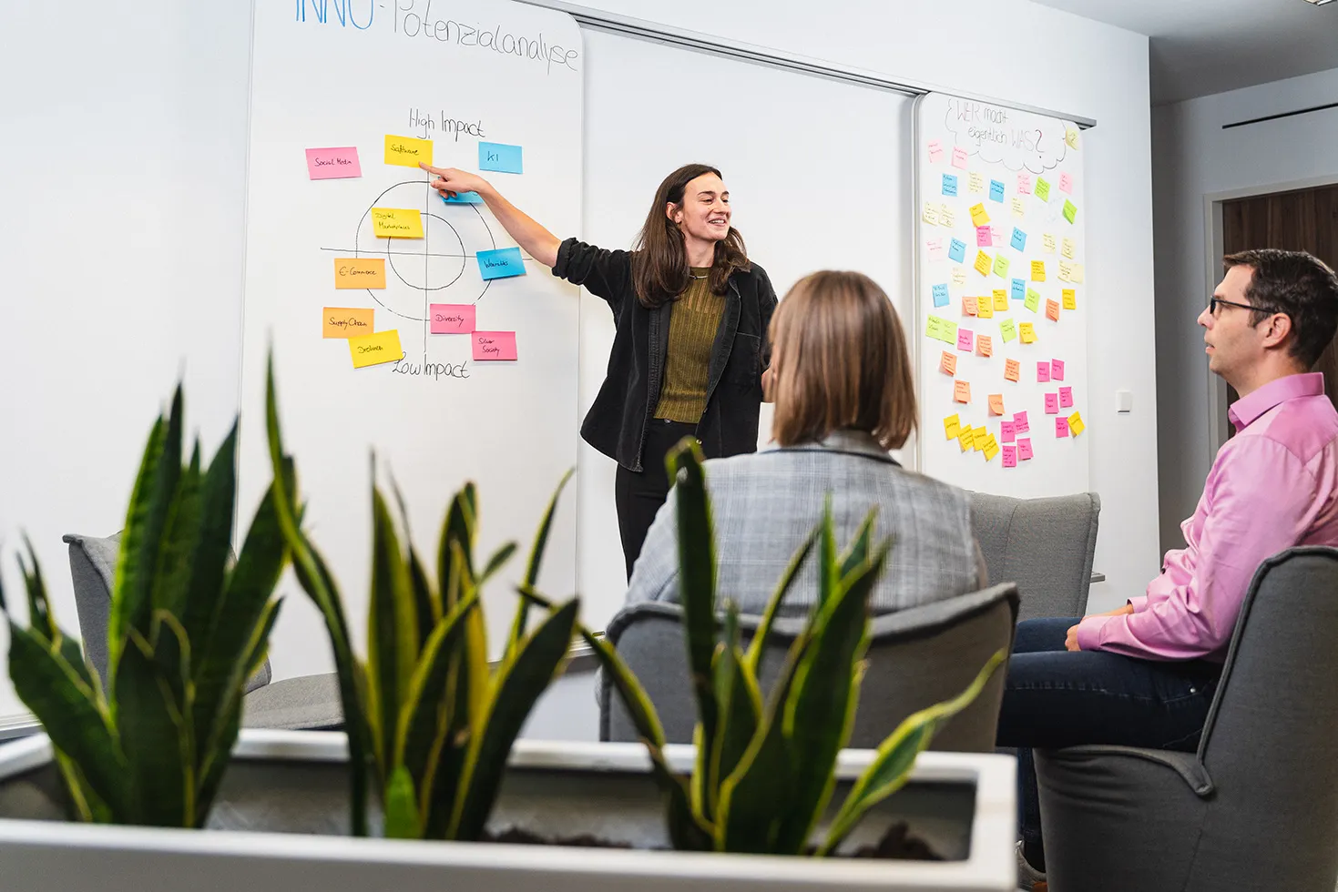 A colleague presents a potential analysis at the whiteboard while two guests listen